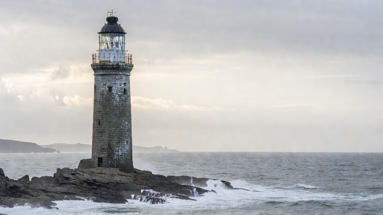 A lighthouse tower standing against a pale coastal horizon